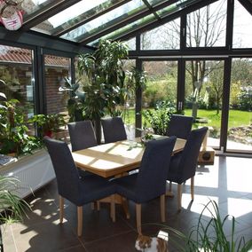 Wintergarten mit Tisch und Stühlen und Pflanzen
